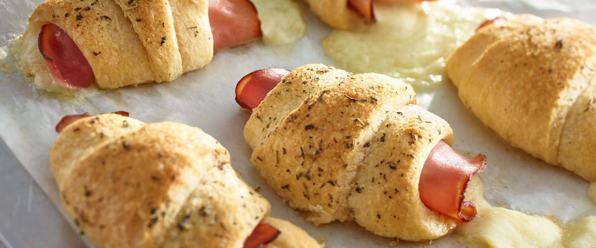 Ham and Havarti Roll Ups with croissants on parchment paper