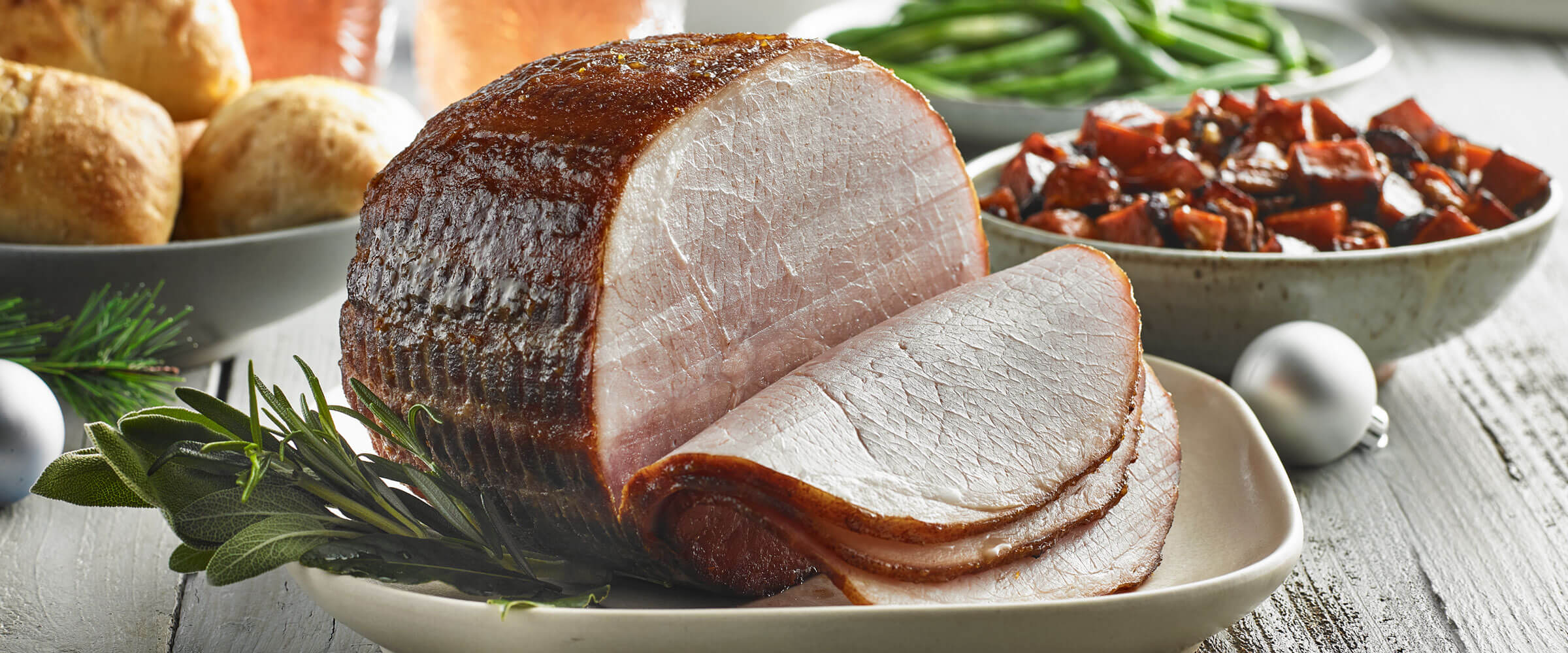 Honey Mustard Ham on white dish sliced with sides in background