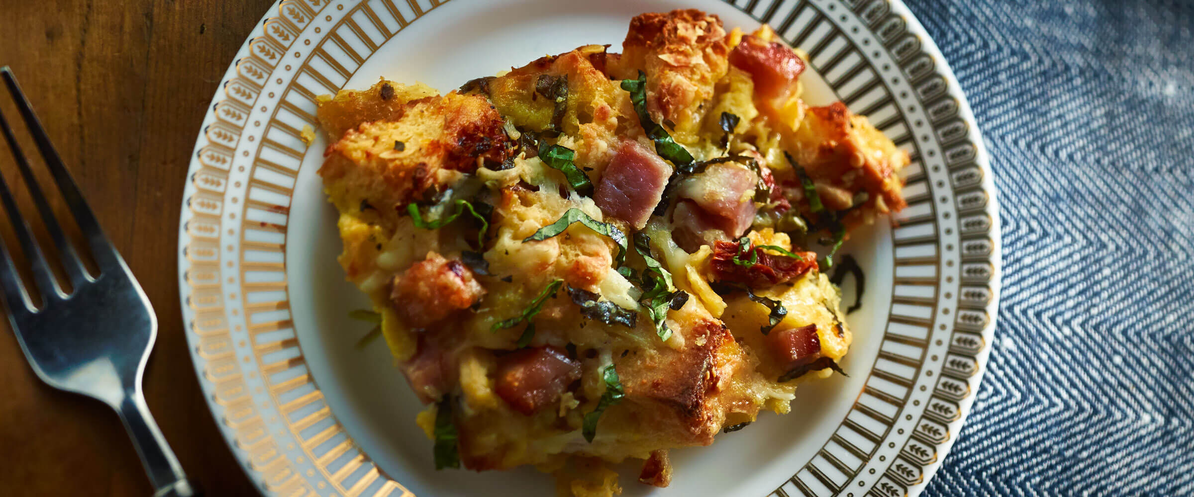 Ham Strata topped with garnish on plate with fork