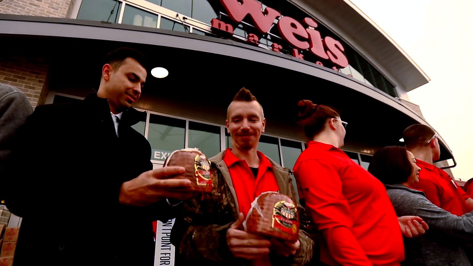 Hams for Hunger participants holding ham package in front of grocery store