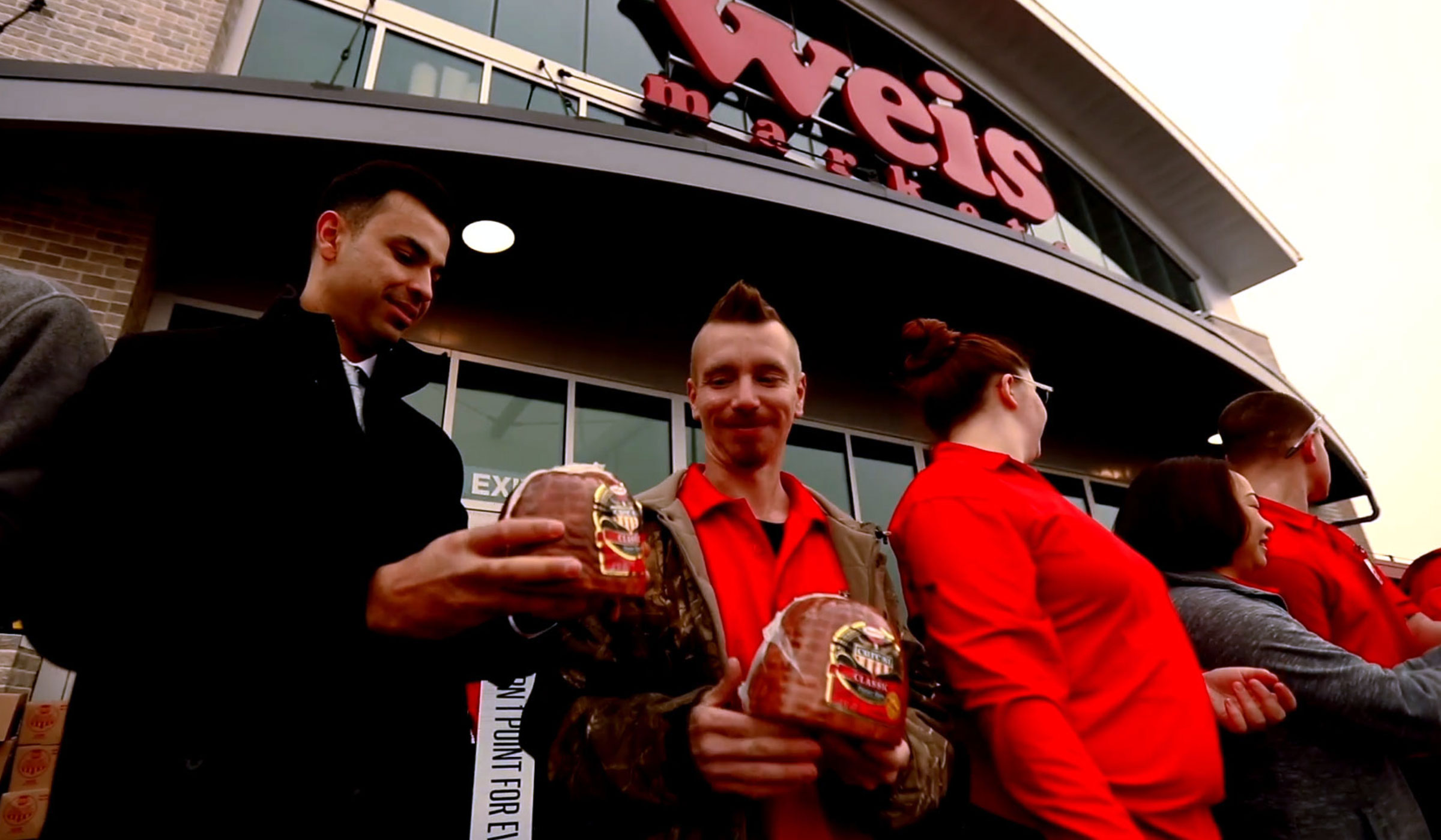 Hams for Hunger participants holding ham package in front of grocery store