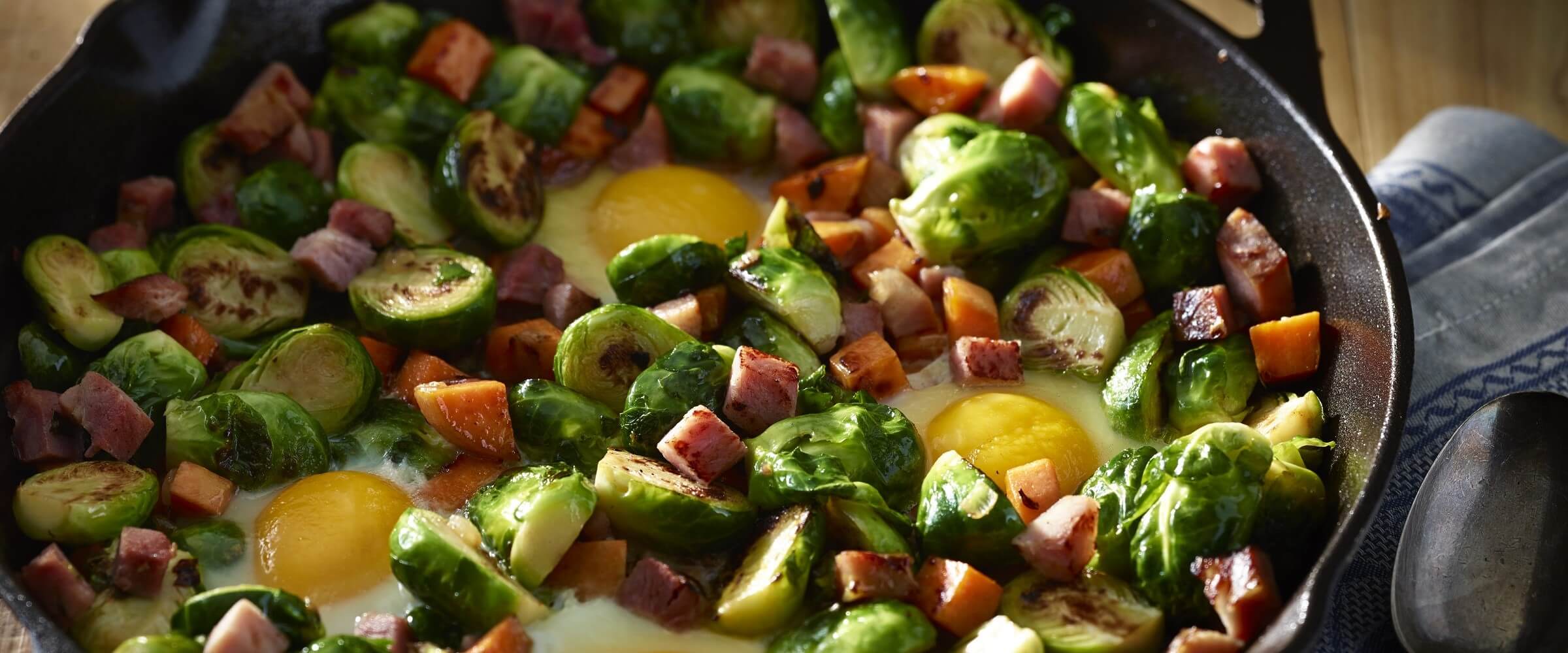 brussel sprout hash with sweet potato and ham and egg in cast iron skillet