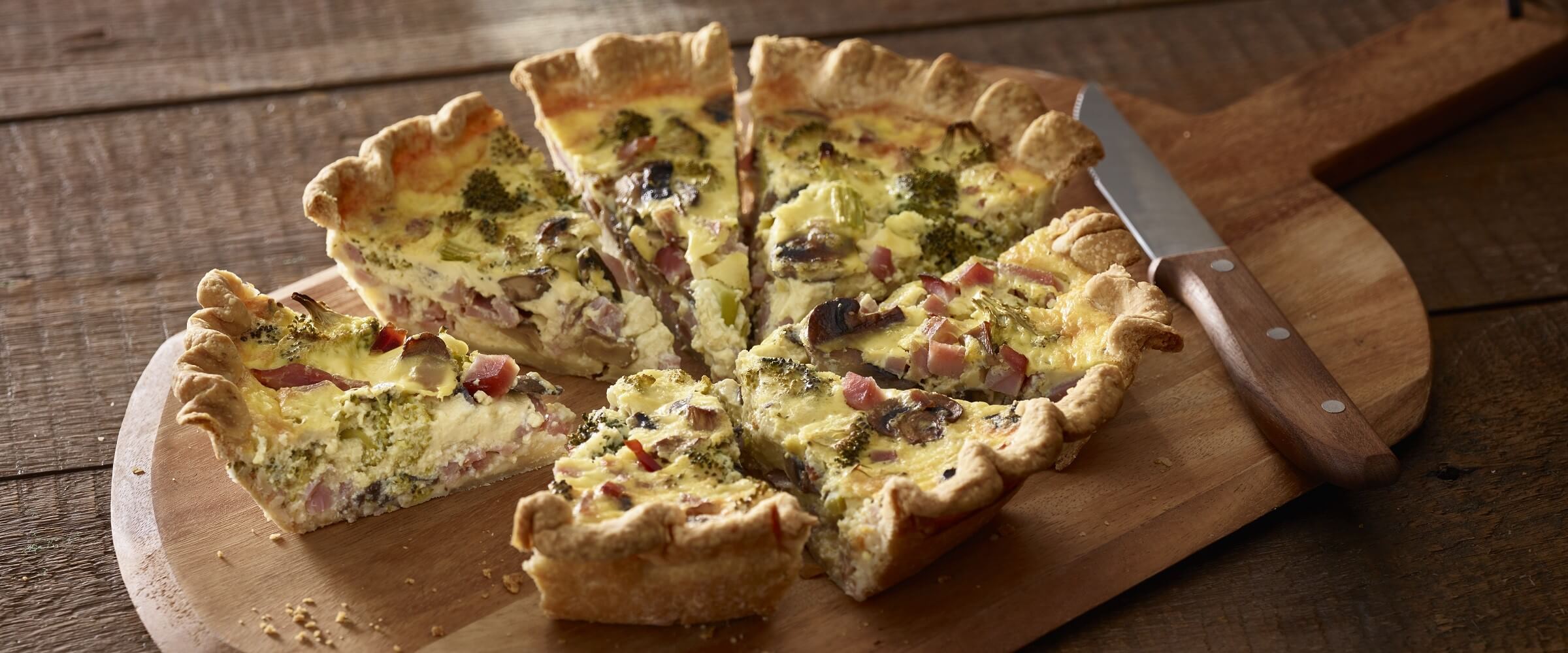 ham broccoli quiche sliced on cutting board with knife
