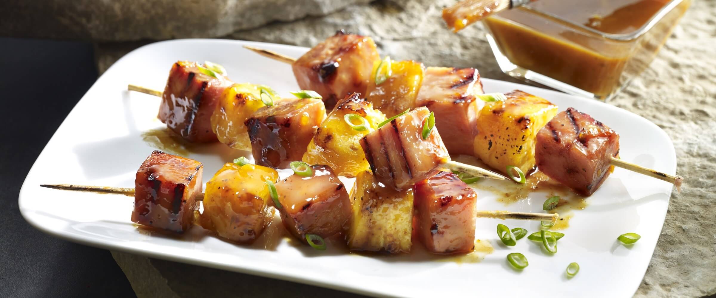 summer ham kabobs with pineapple on white plate with glaze