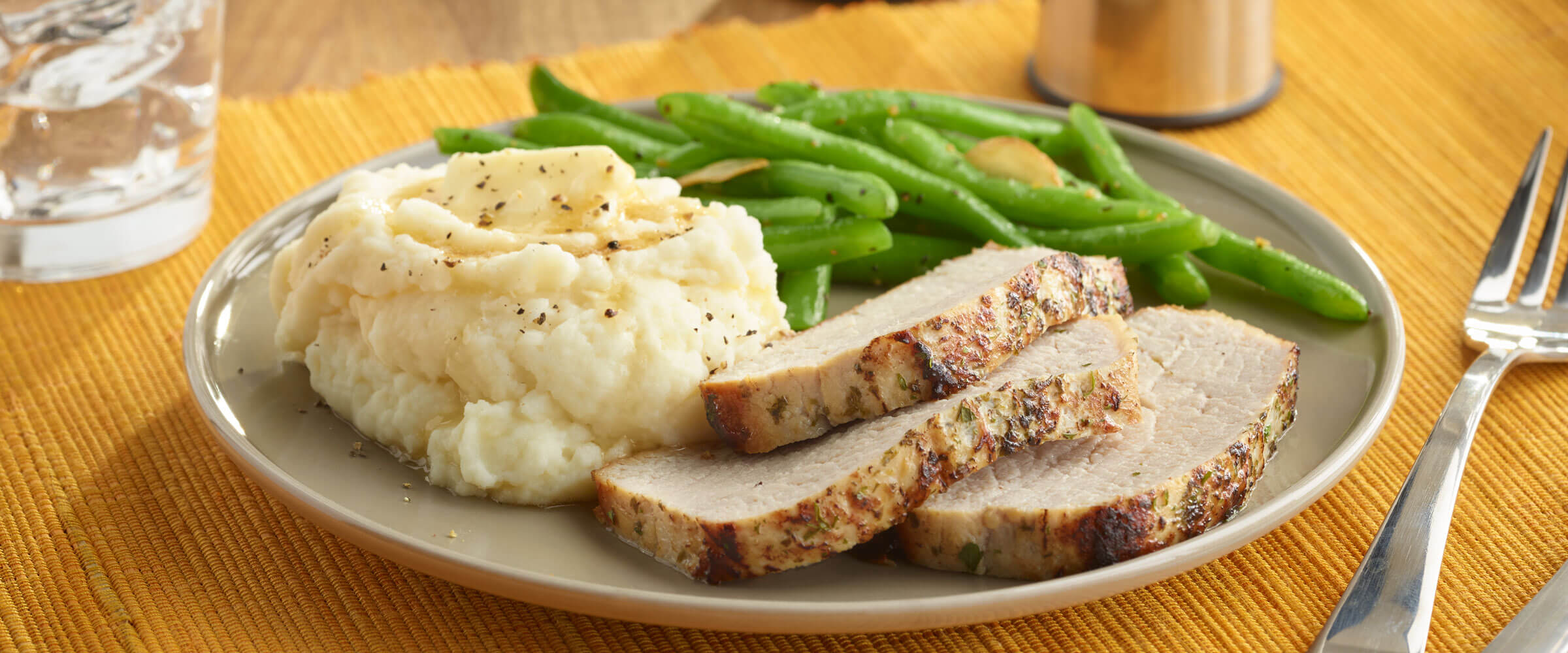 Pork Loin Filet and Mashed Potatoes with green beans on plate on orange placemat