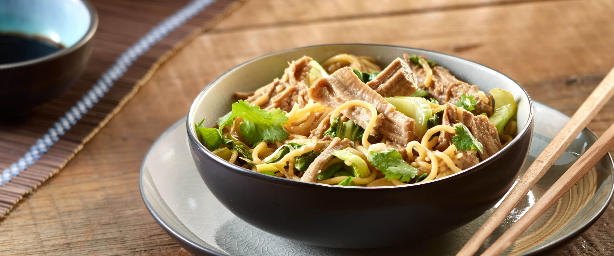 Slow Cooker Pork with Noodles in black bowl with chop sticks