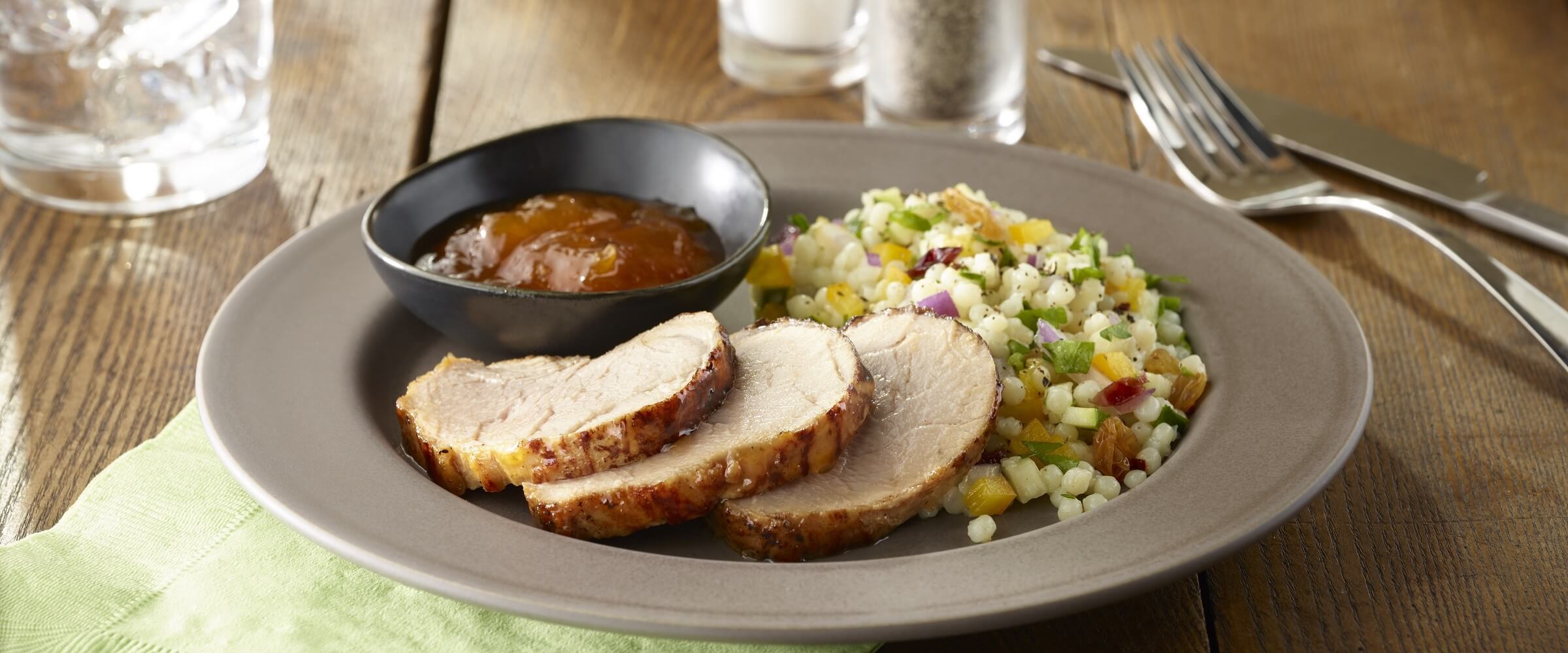 amazing apricot pork tenderloin with couscous and dipping sauce on tan plate