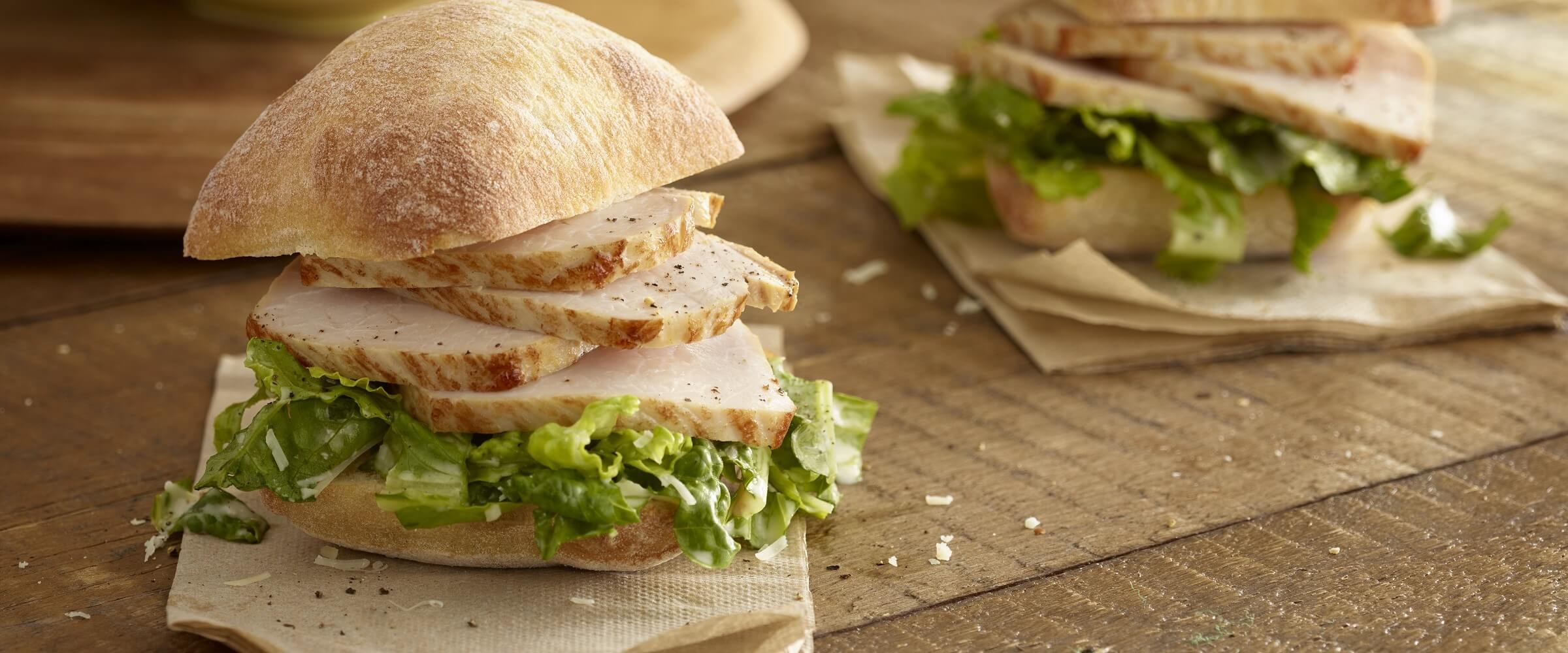 caesar pork loin sandwich on tan napkin on wood table