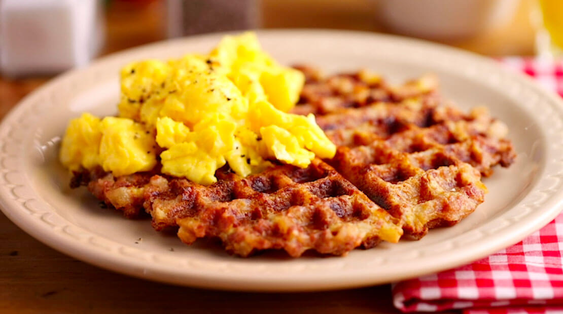 Hash Waffle Iron topped with eggs on red and white checked napkin