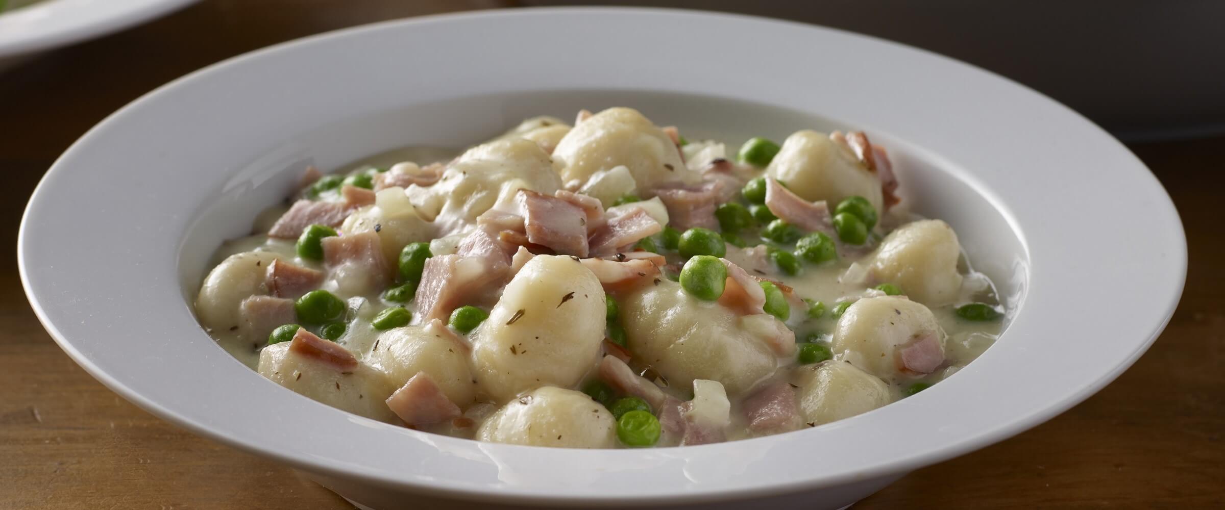 gnocchi skillet with ham and peas in white bowl