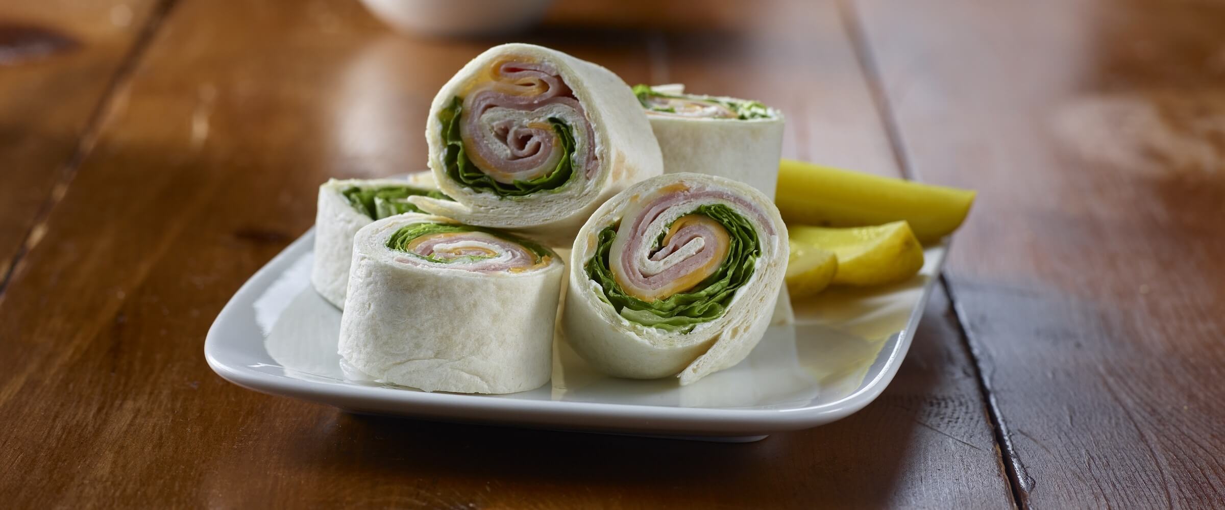 ham and cheese pinwheels on white plate with pickle spears