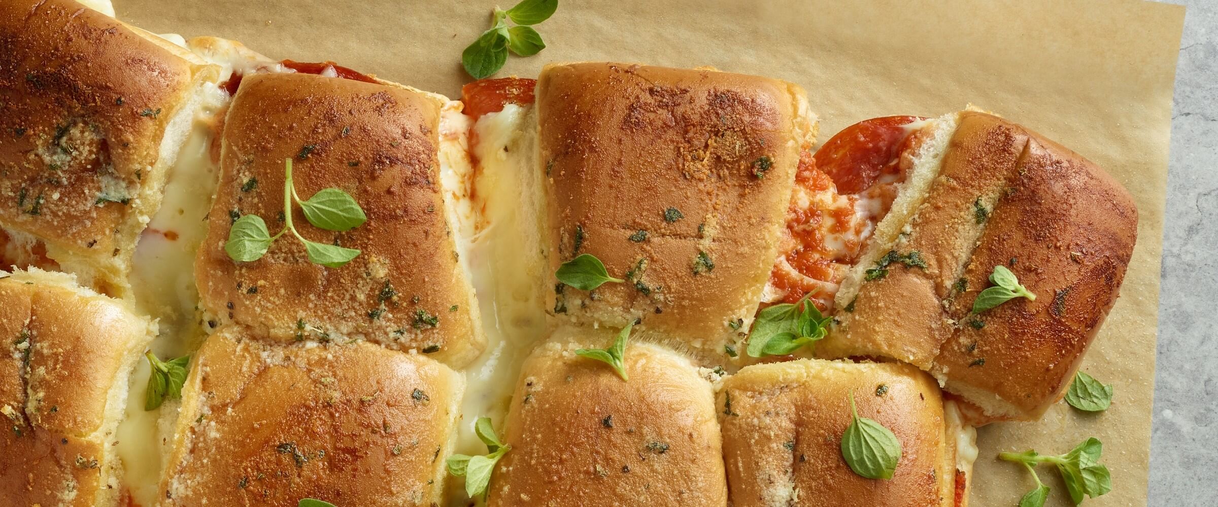 pull apart pizza sandwiches topped with garnish on parchment paper
