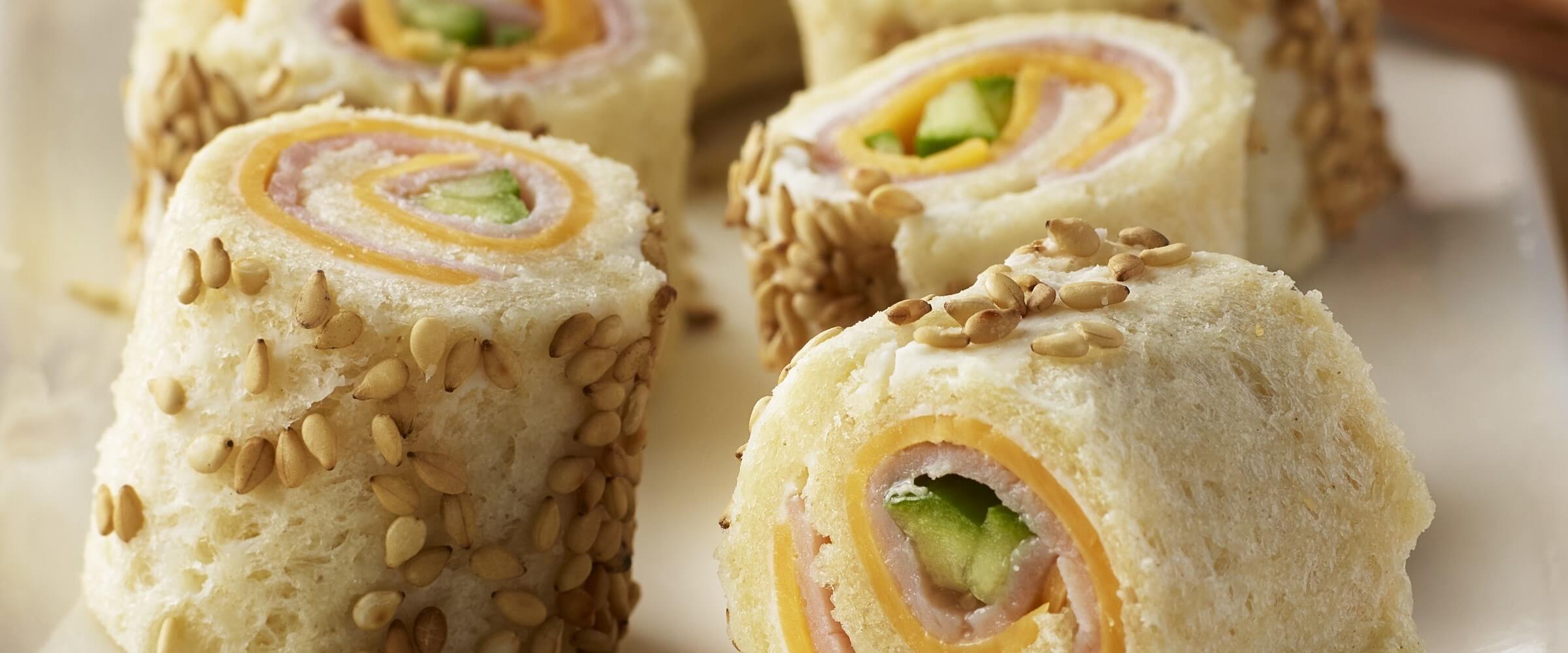 ham and cheese sushi rolls with seeds on white platter