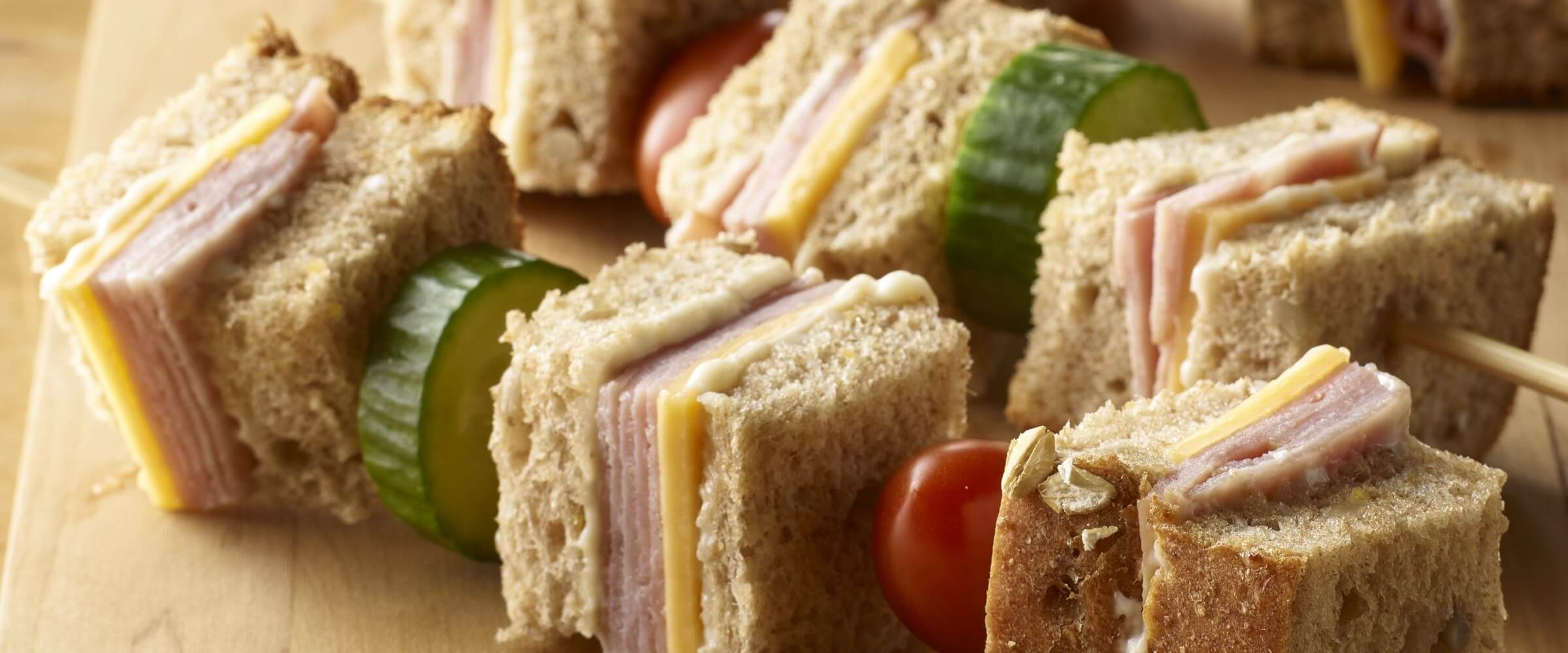 ham and cheese sandwich kabobs with vegetables on wood platter