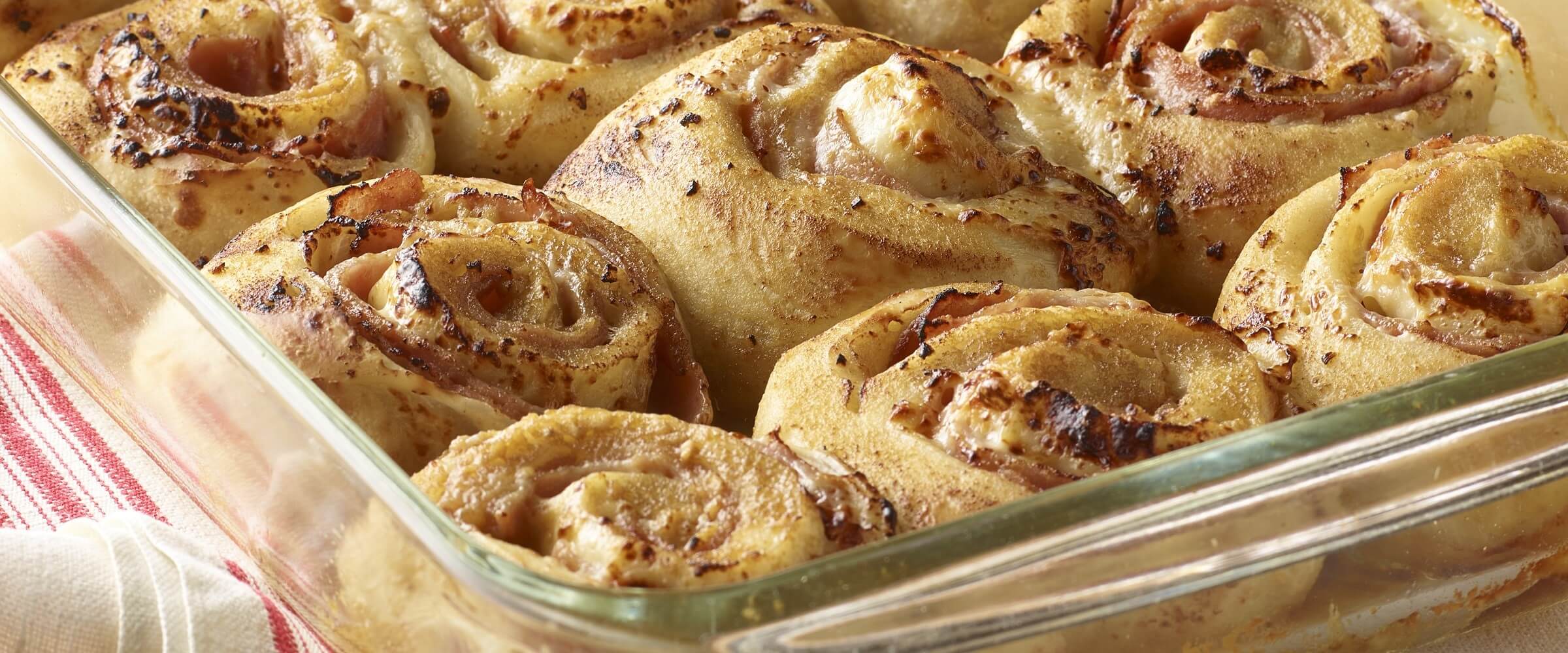 Savory ham and cheese rolls in clear baking dish