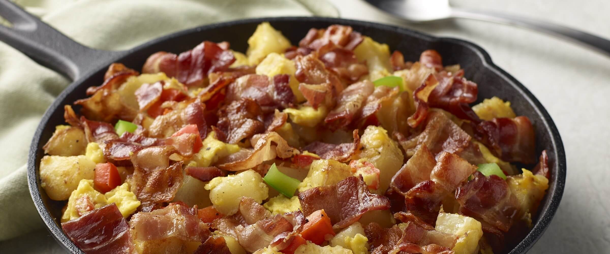 skillet breakfast in cast iron pan topped with bacon