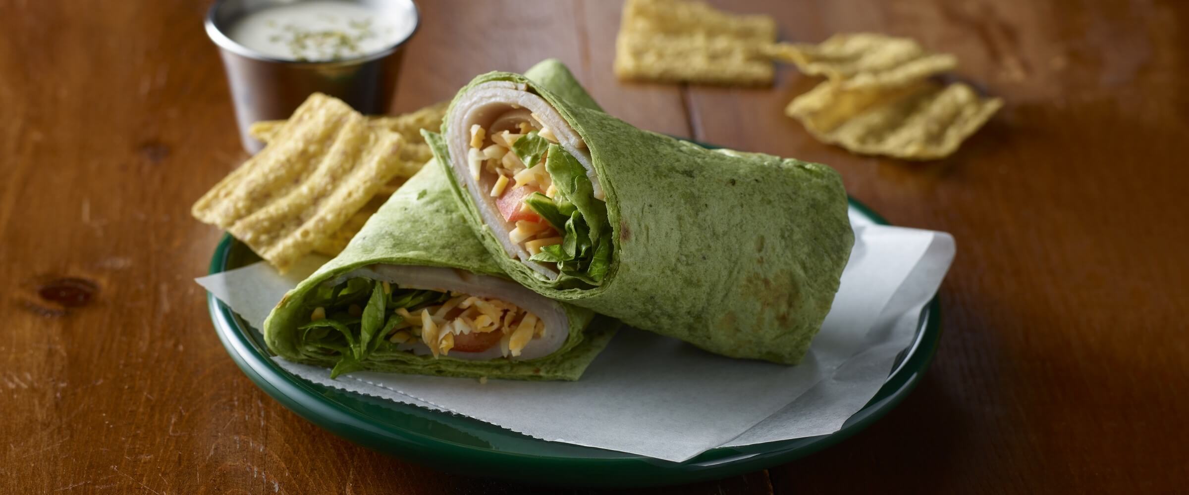 turkey ranch wrap in green tortilla with chips on the side