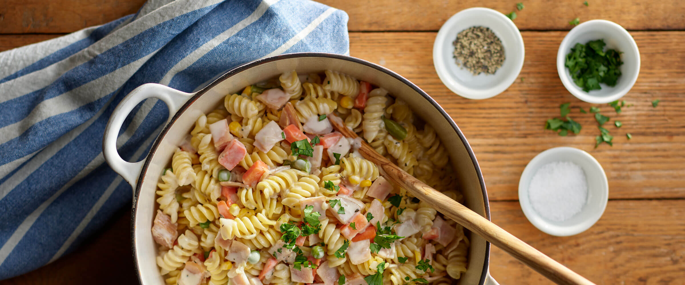 One-Pot Turkey Pot Pie Pasta in white pot with serving spoon and black and white linen