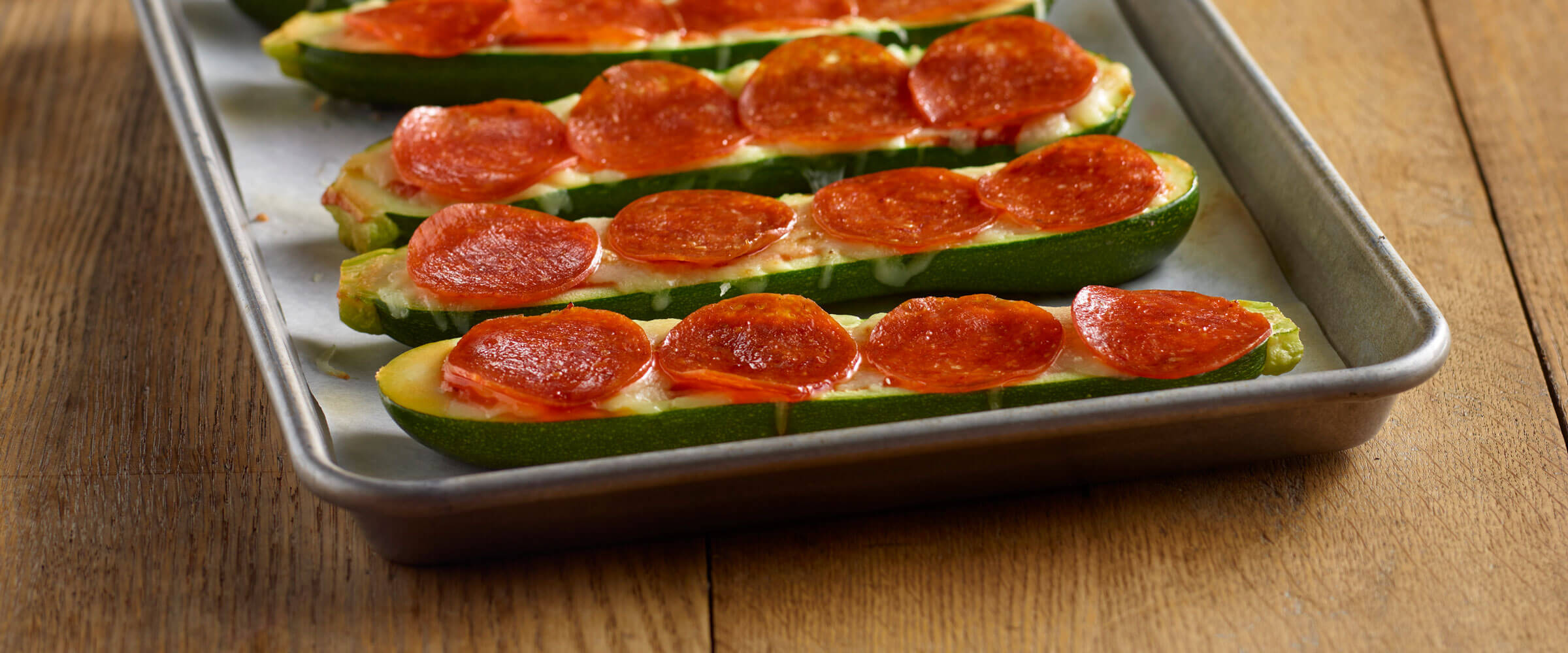 Pepperoni and cheese topped zucchini boards on metal sheet pan