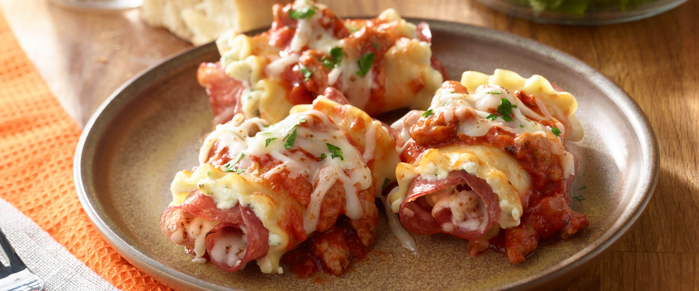 Salami and Sausage Lasagna Rolls topped with cheese and garnish on plate