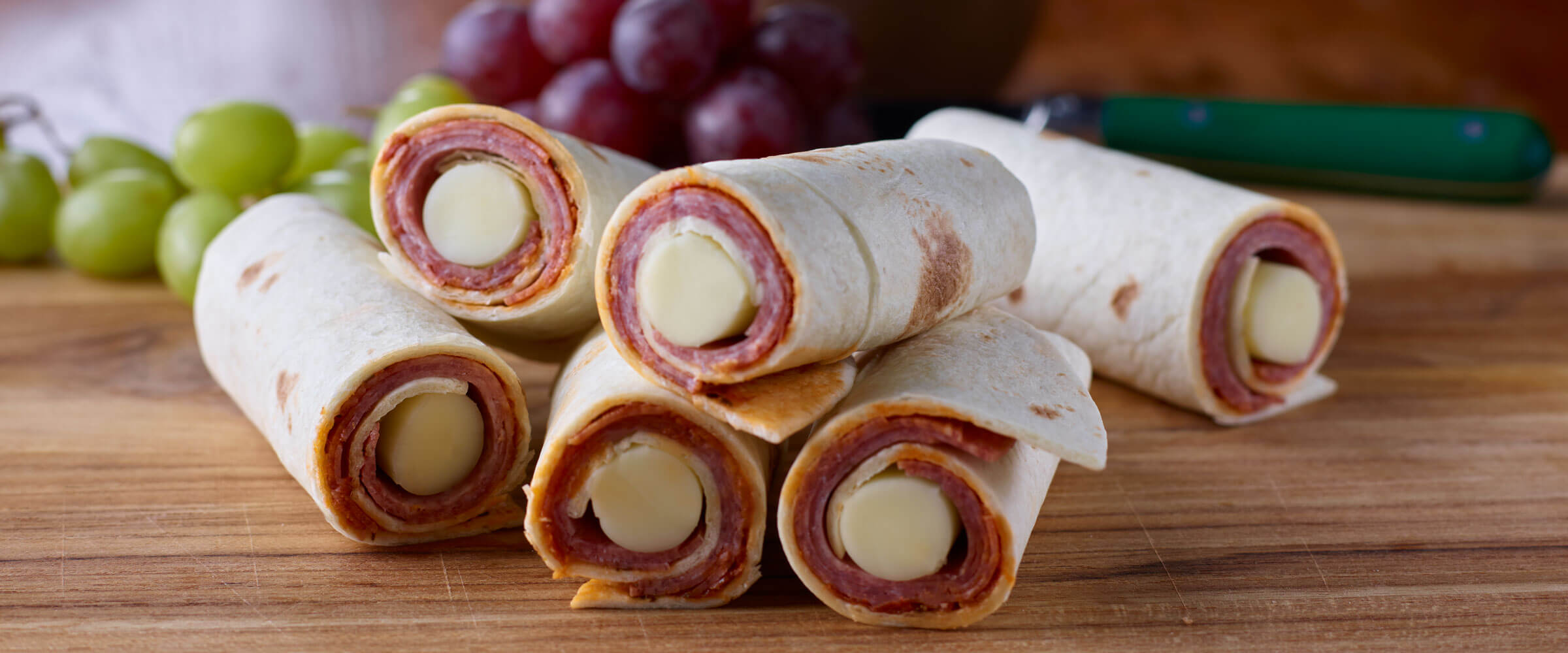 Salami Wrapped cheese with tortilla on wood baord