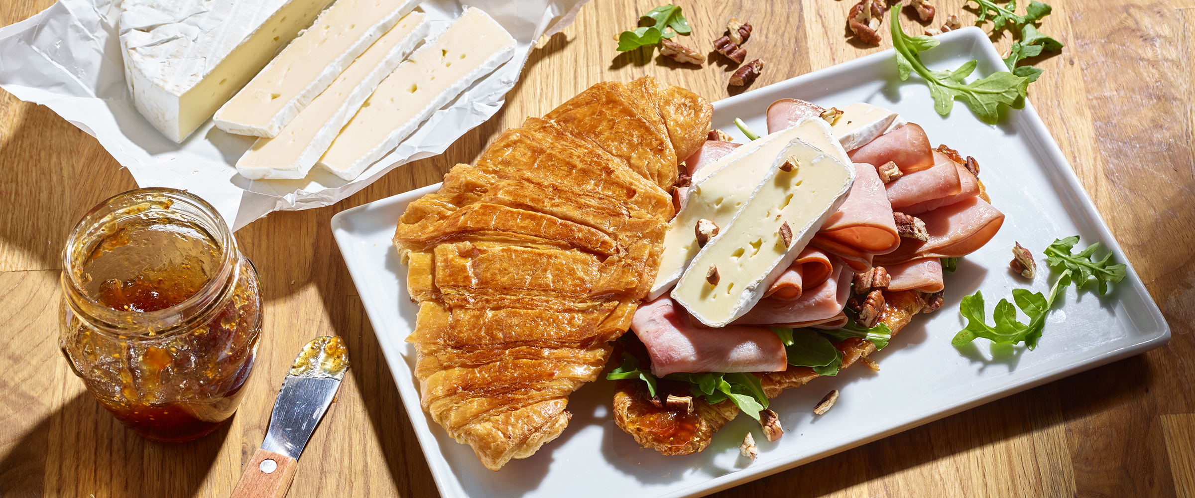 Candied Croissant Cherrywood Ham And Brie Sandwich on a platter with jam