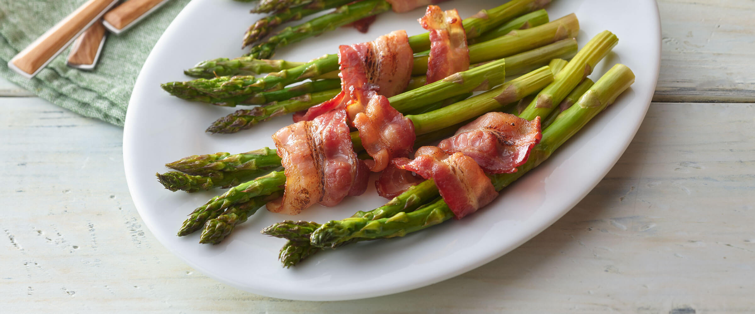 Bacon Wrapped Asparagus on white plate with green napkin
