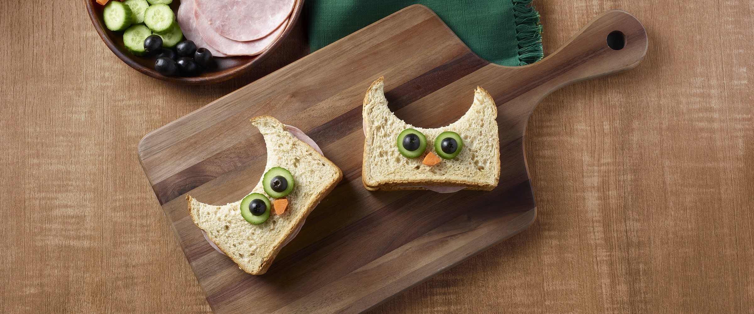 ham and cheese owls shaped sandwich cutouts on wood board