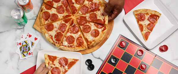 Pepperoni pizza on table for game night with cards and checker board