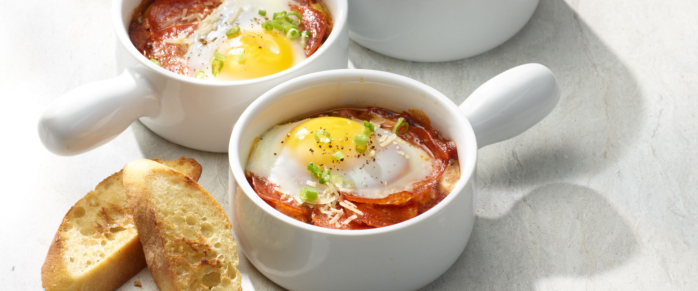 Pepperoni Baked Eggs in individual cups with slides of baguette on the side