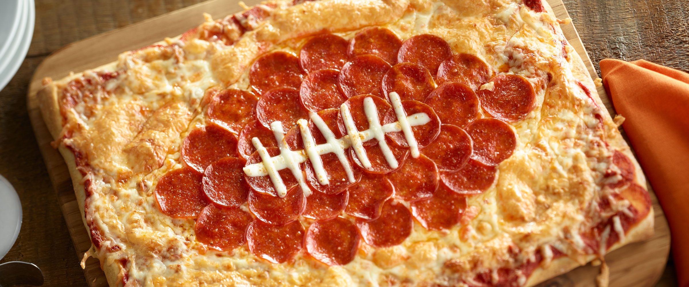 Football shaped Pepperoni Pizza on cutting board