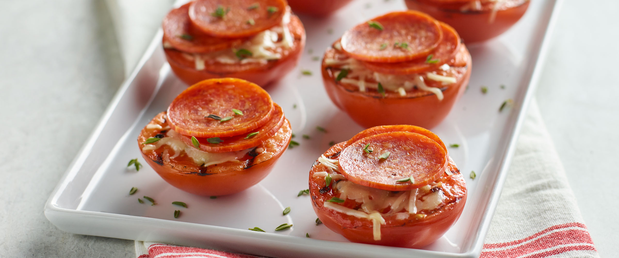 Garlic Grilled Tomatoes with Pepperoni on white platter topped with chives