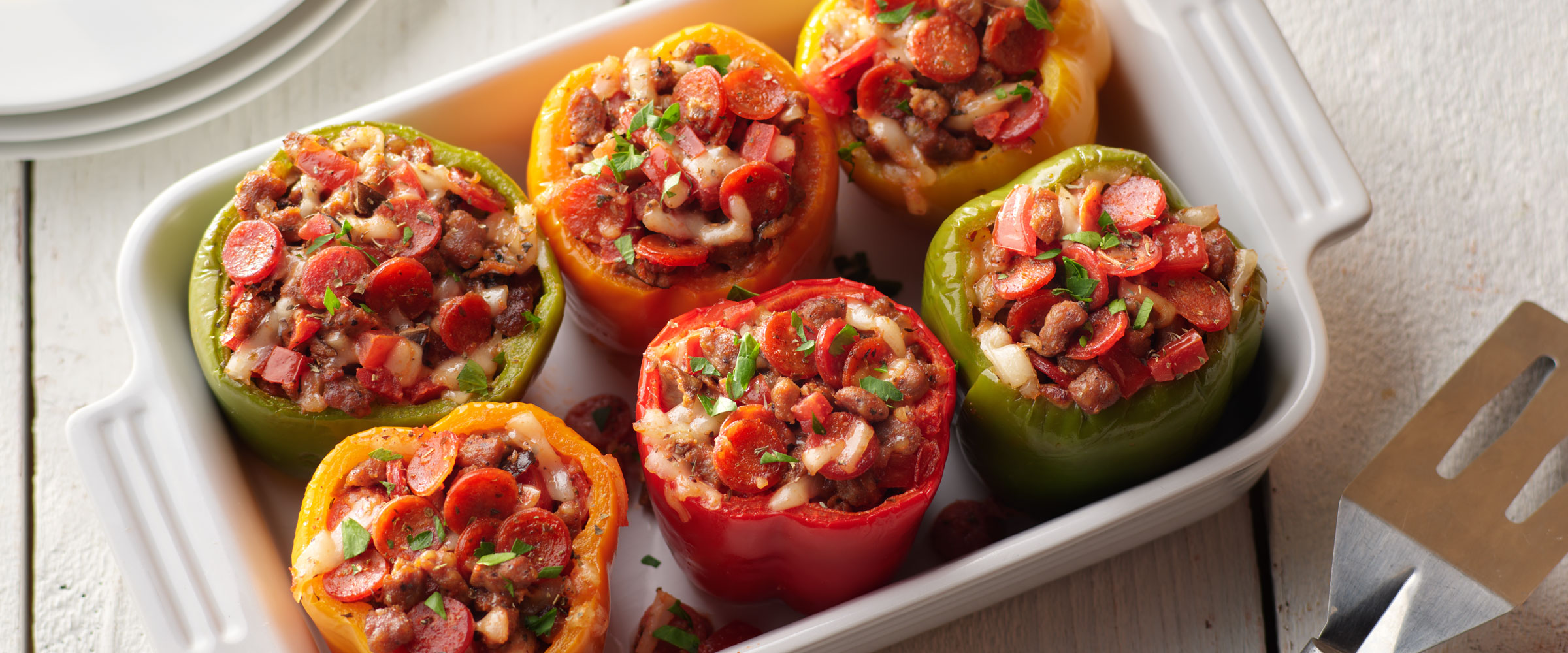 Pepperoni Stuffed Peppers in white baking dish with spatula