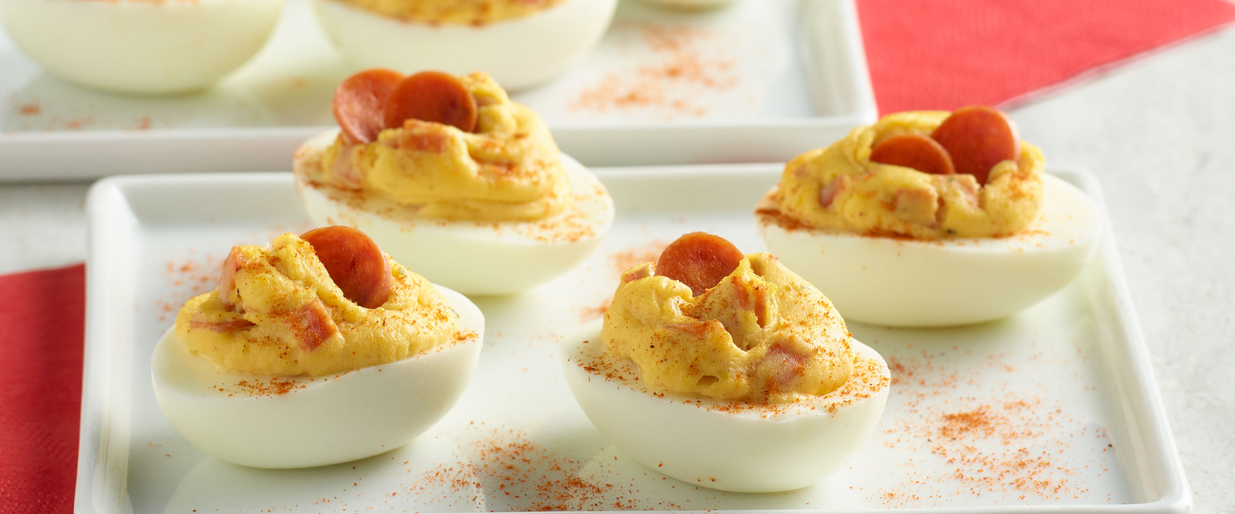 Pepperoni Stuffed Deviled Eggs on white platter topped with paprika