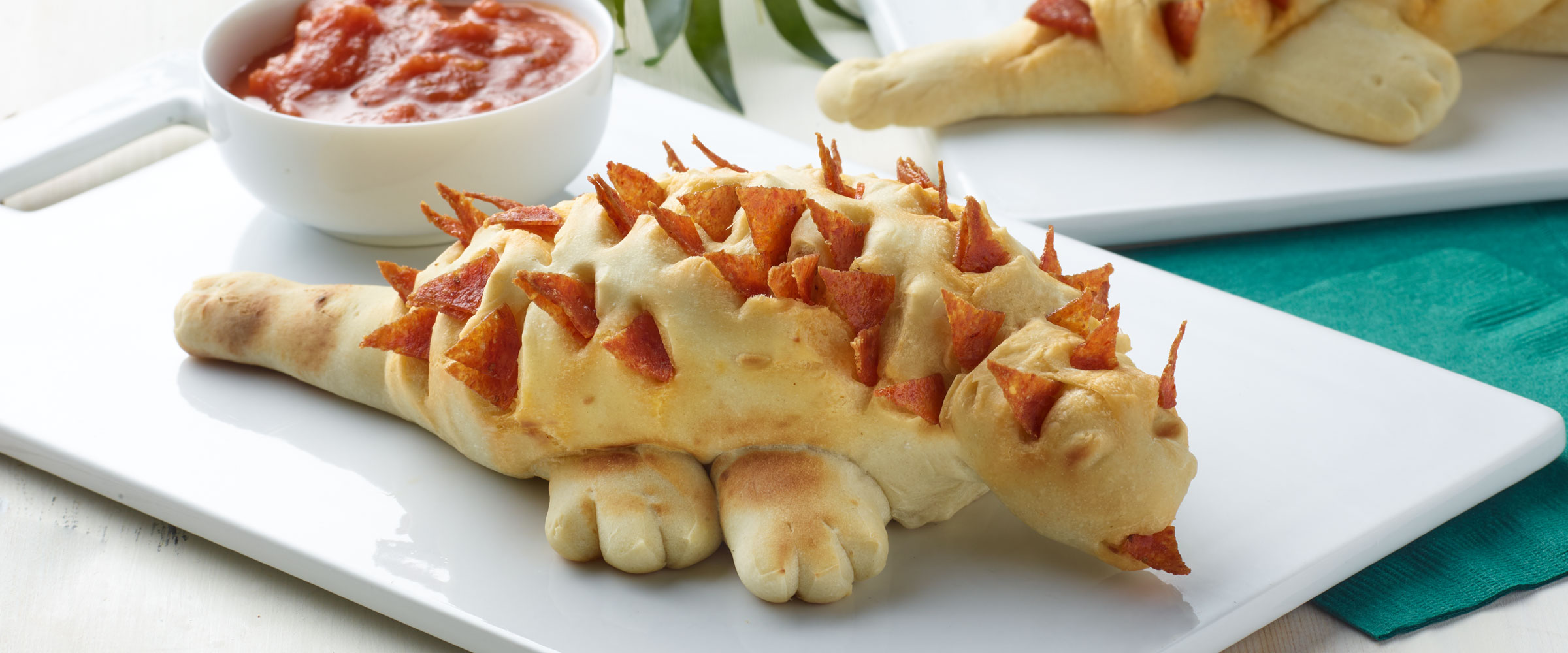 Pepperoni Dino Bread on white plate with dipping sauce