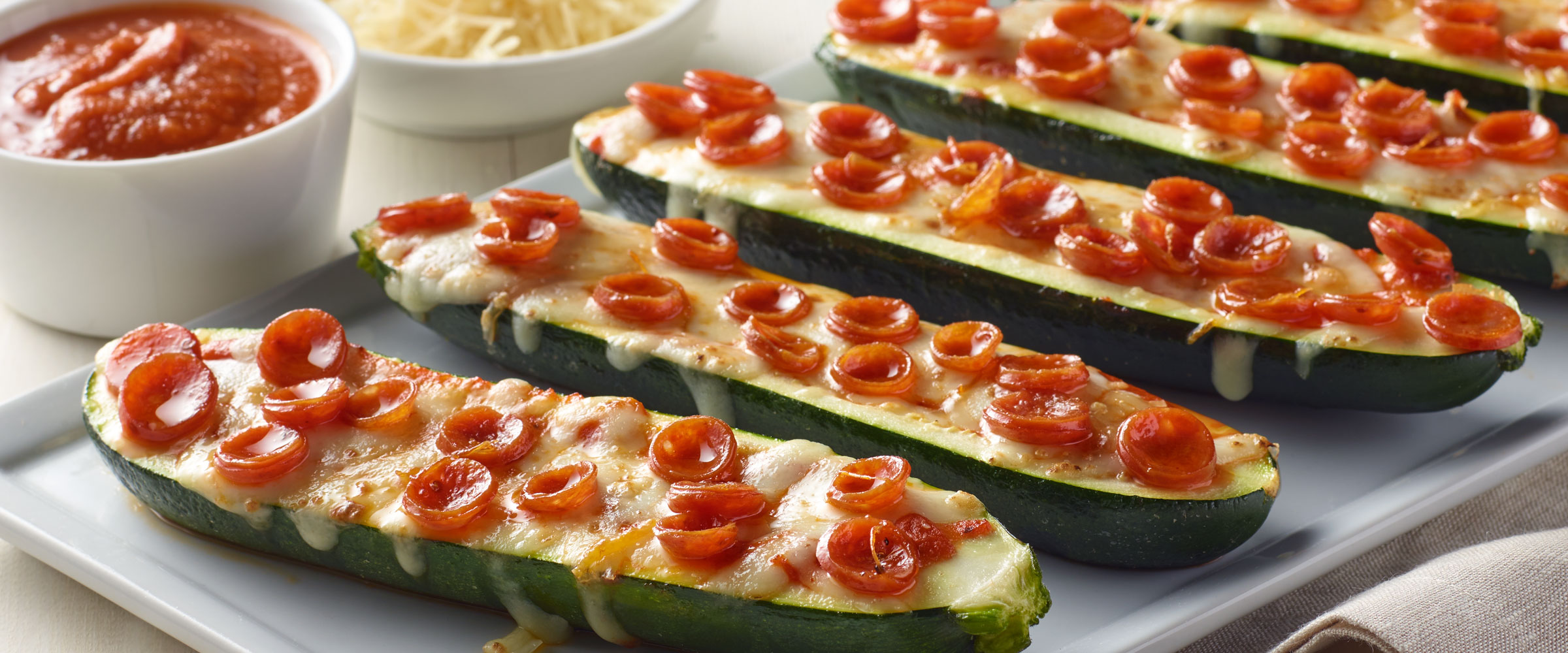 Pepperoni Mini Zucchini Boats on white platter with dipping sauce