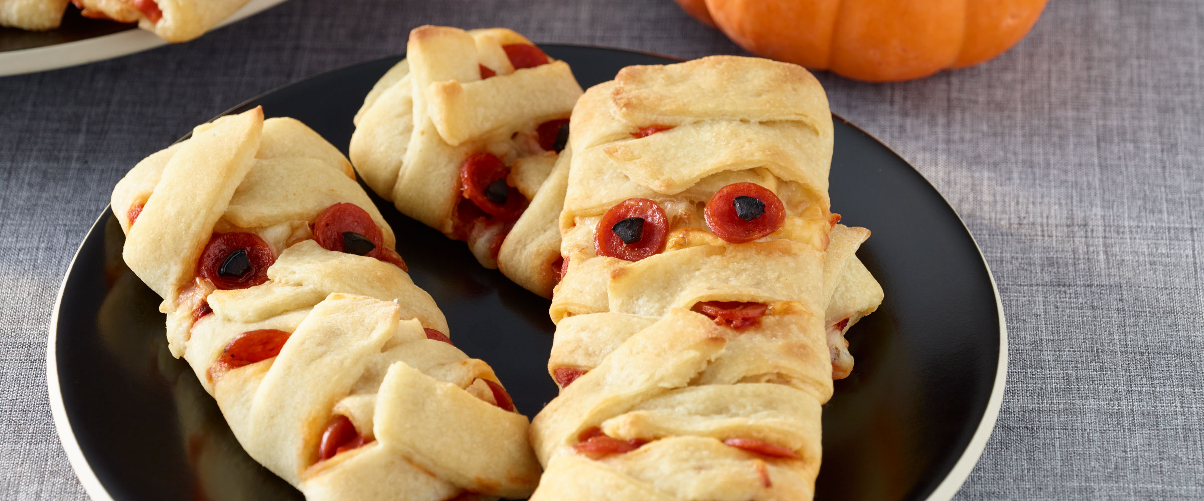 Pizza Mummy wrapped pastry on black plate