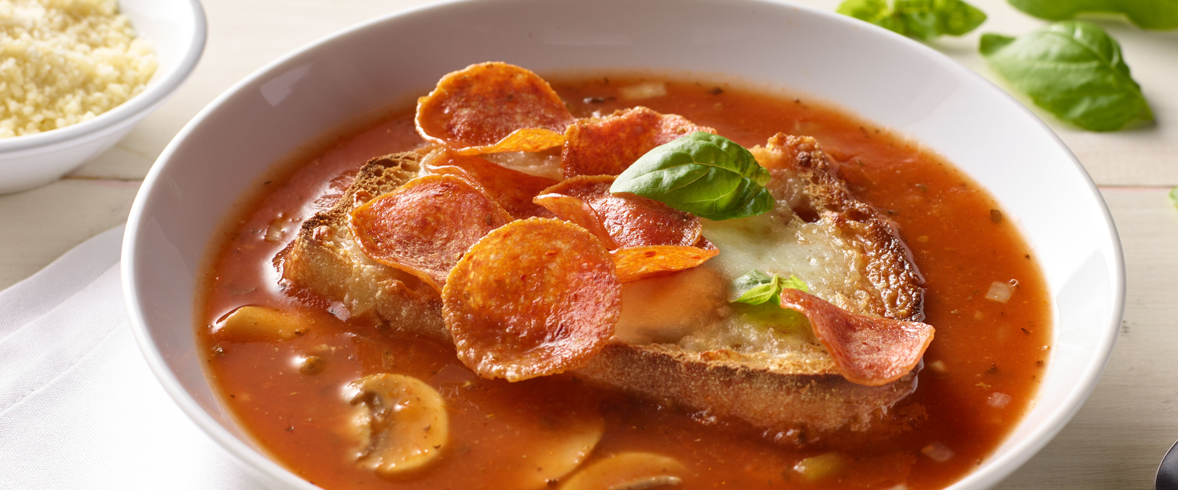 Pepperoni Pizza Soup with slice of bread in white bowl