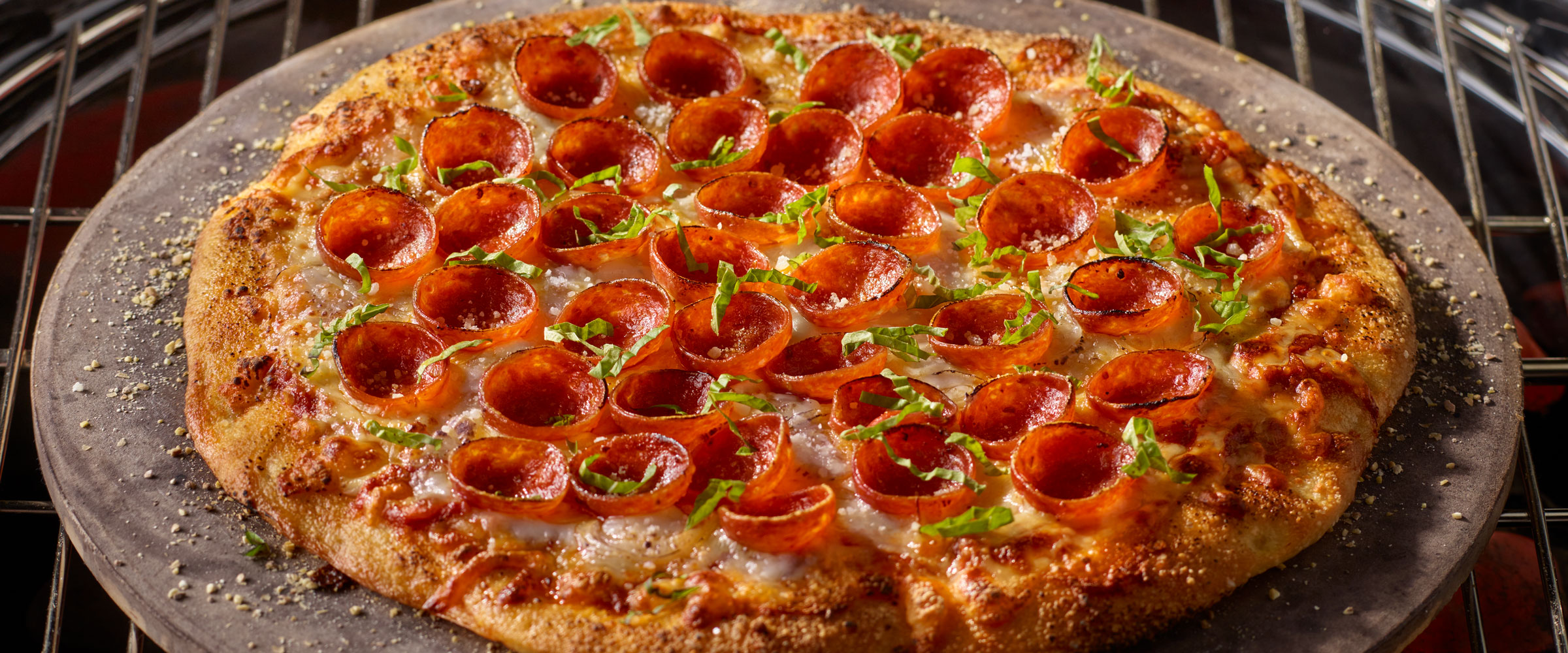 Grilled NY HORMEL® Pepperoni Cup N’ Crisp Pizza on pizza pan topped with garnish