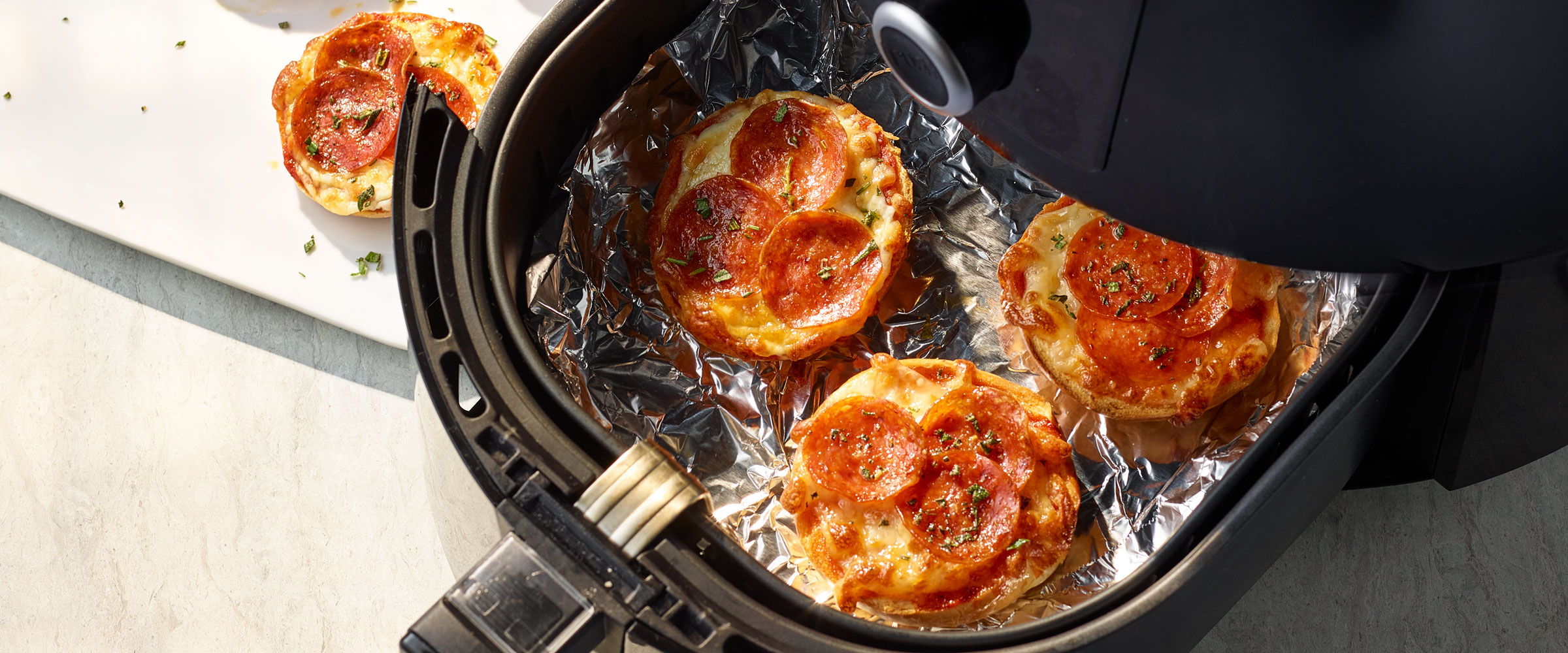 Air Fryer Pepperoni Pizza Bagels on tin foil in fryer