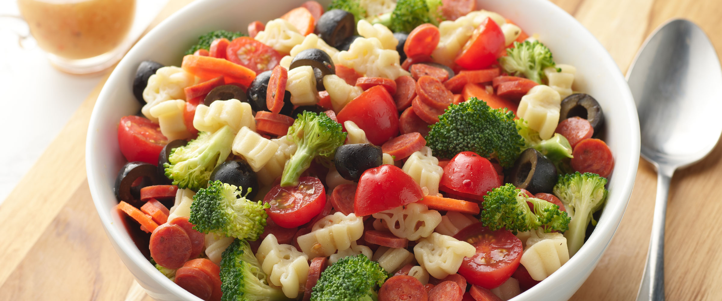 Dinosaur Pasta Salad with tomatoes and broccoli in white bowl