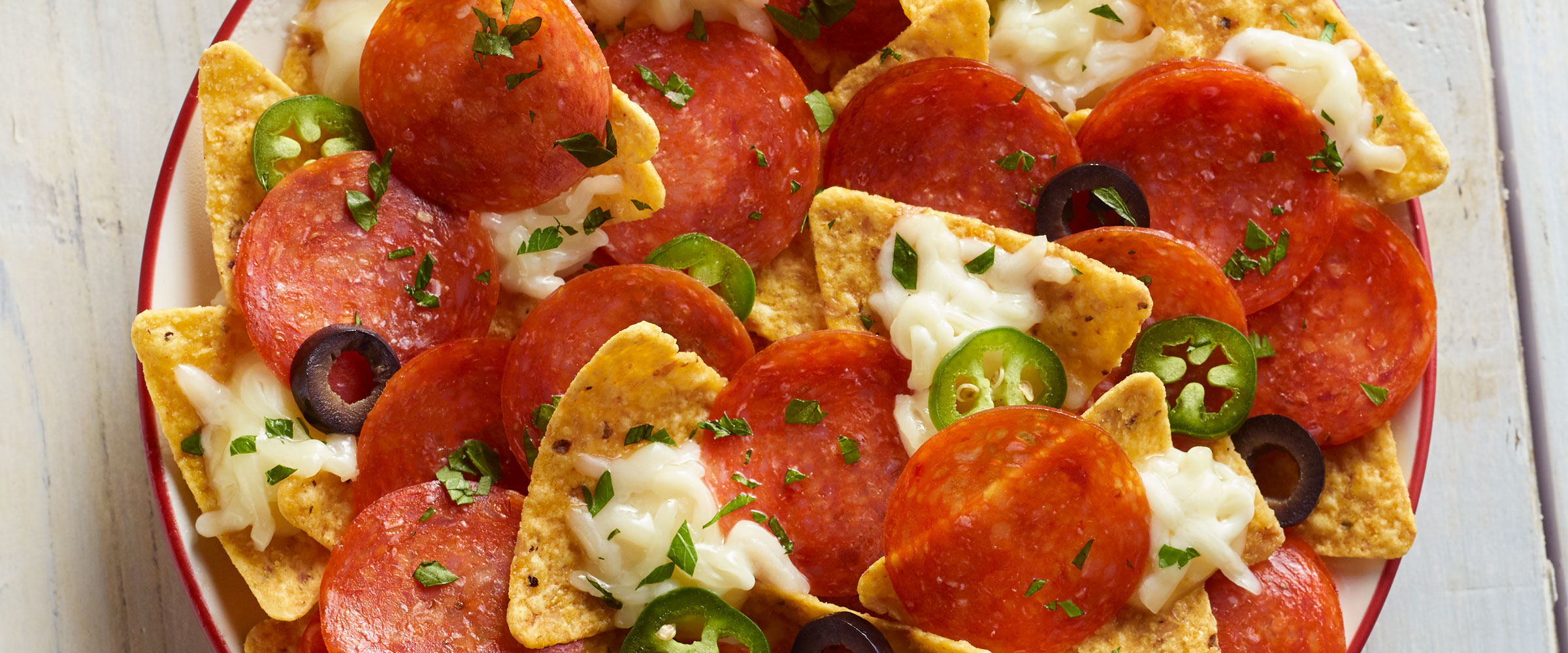 Pepperoni Nachos topped with jalapenos in dish