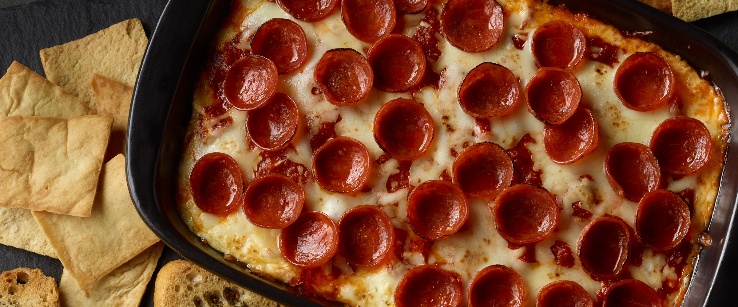 Pepperoni Pizza Dip in dish with pita and bread for dipping