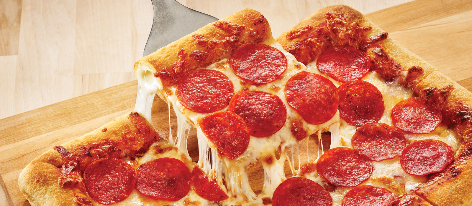 A spatula holding a slice of square cut pepperoni pizza