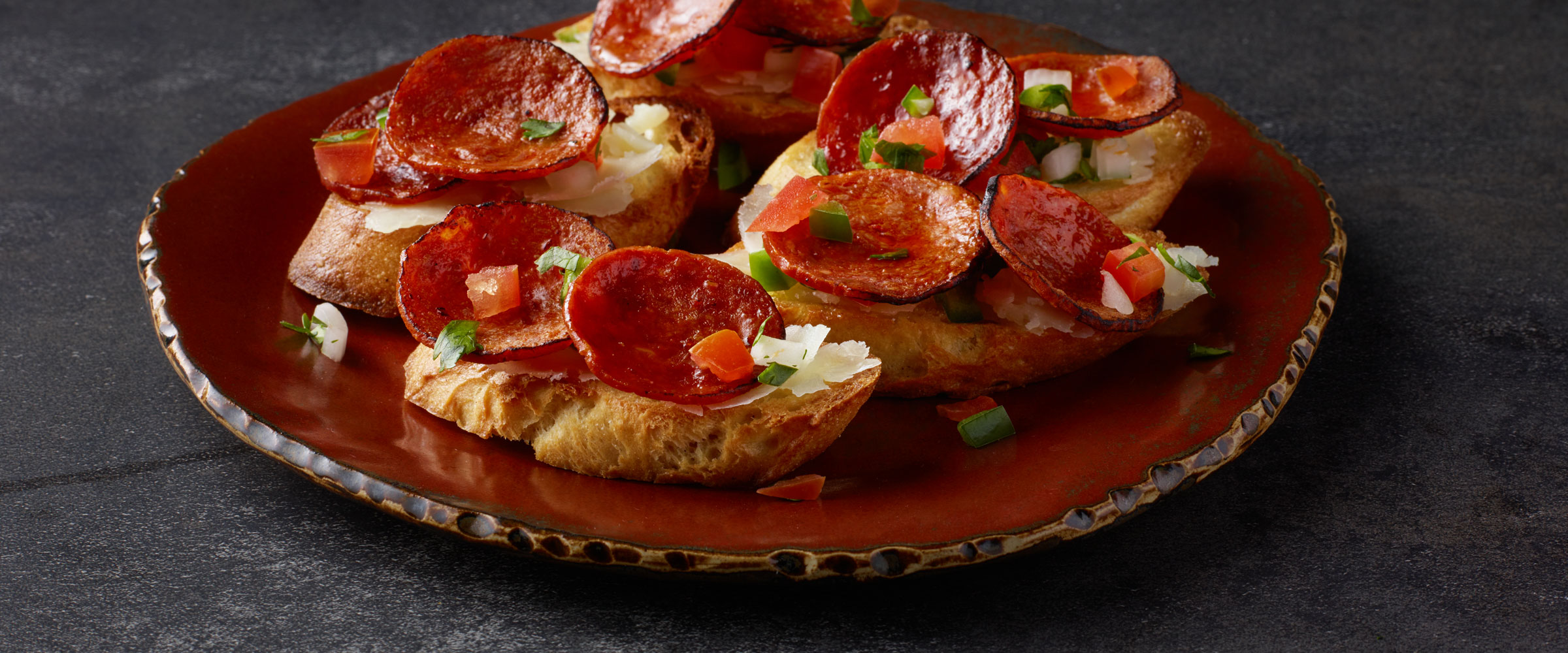 Chorizo Toasts with Manchego and Pico on red plate