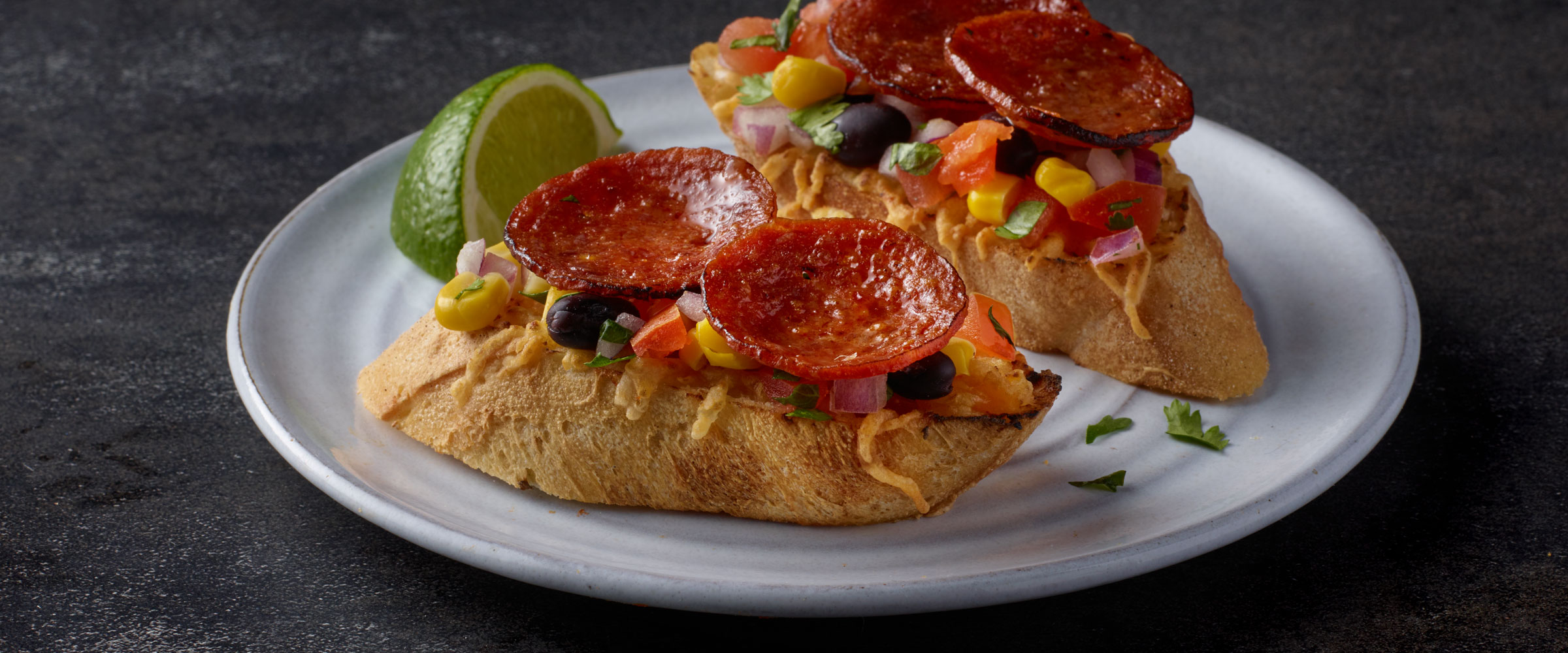 Chorizo Toasts with Black Bean Salsa on plate with lime wedge