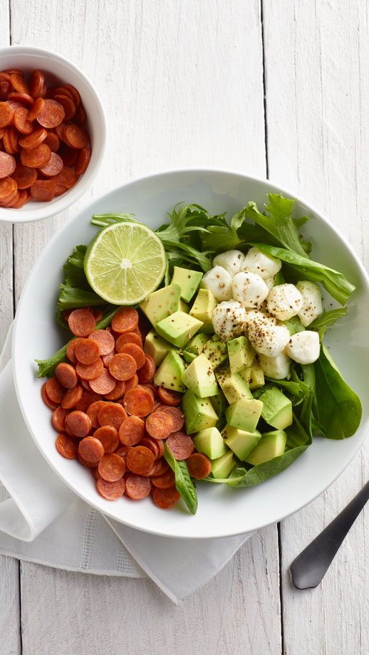 Close up of a green salad with avocado, mozzarella and mini pepperoni