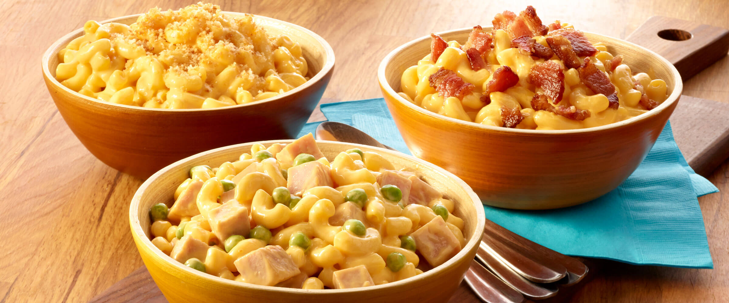 Macaroni and Cheese 3 ways with bacon, breadcrumbs, ham and peas with blue napkin