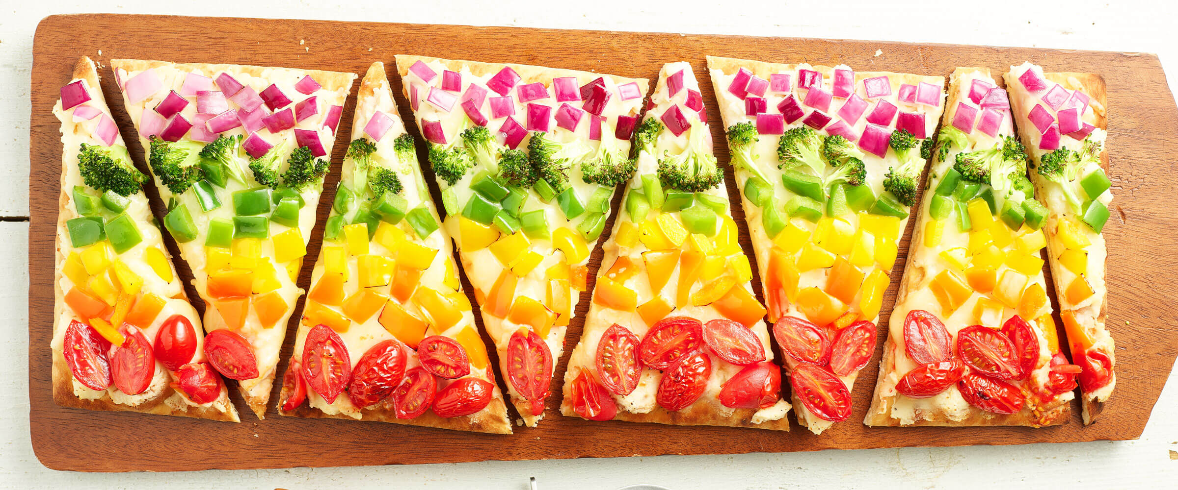 Mashed Potato Rainbow Flatbread Pizza cut into triangles on wood board