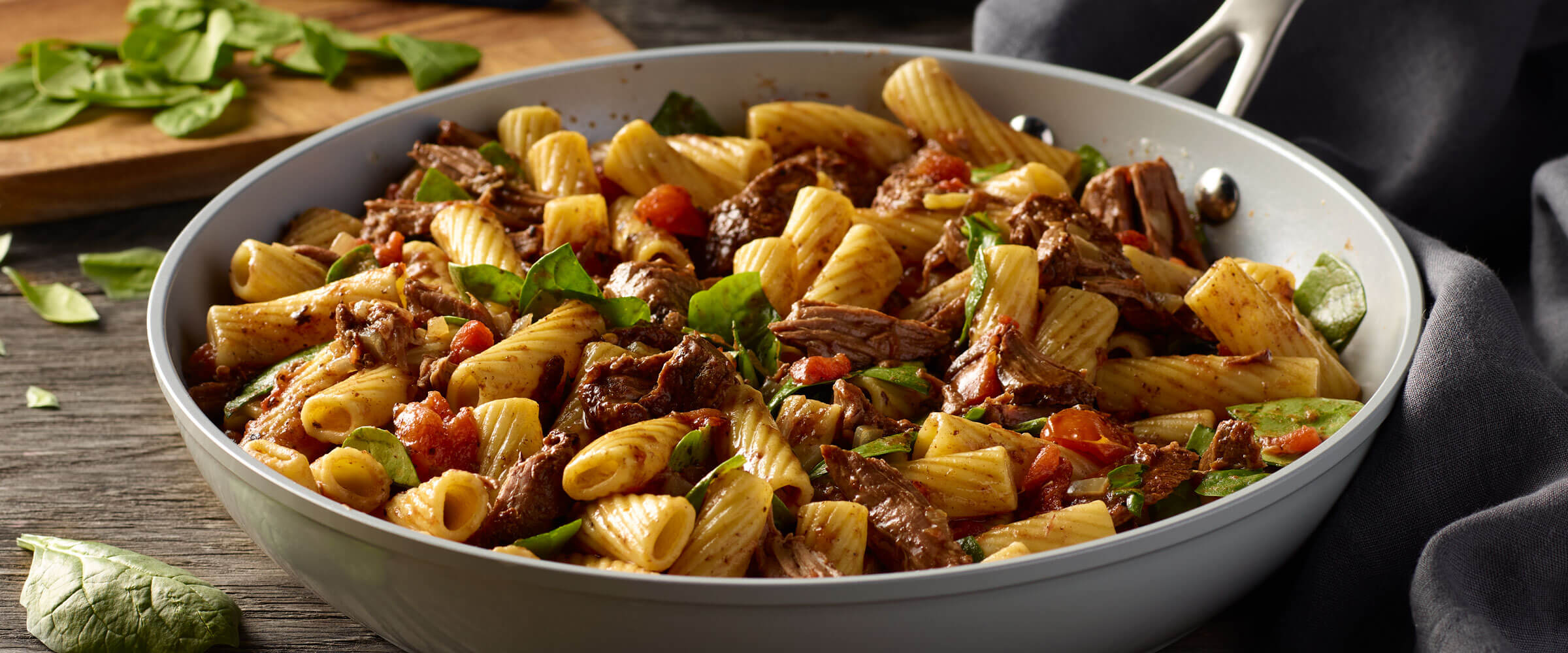 Beef Roast Pasta Skillet in gray pan topped with greens